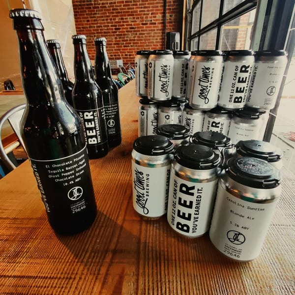 Bottles and cans of "Good Times Brewing" beer, including "El Chocolate Picante" stout and "Carolina Sunrise" blonde ale.